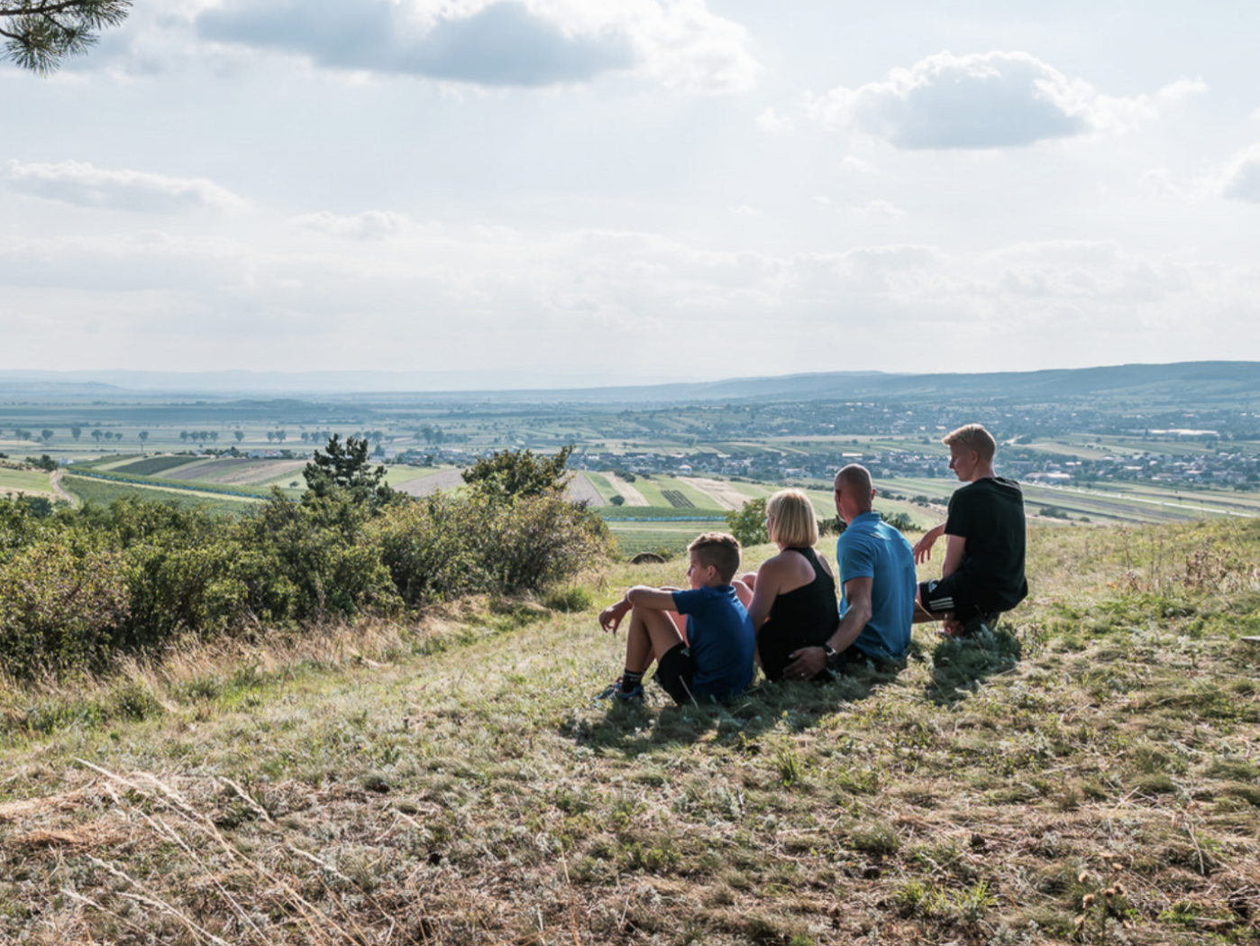 Familie beim Naturbeobachten auf einer Anhöhe mit Blick über die burgenländische Landschaft